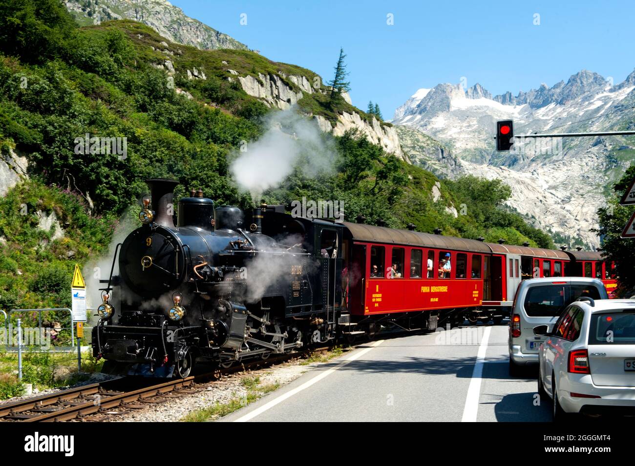 Furka Cogwheel Steam Railway crossing the Furka Pass mountain road, Furka region, Valais, Switzerland Stock Photo