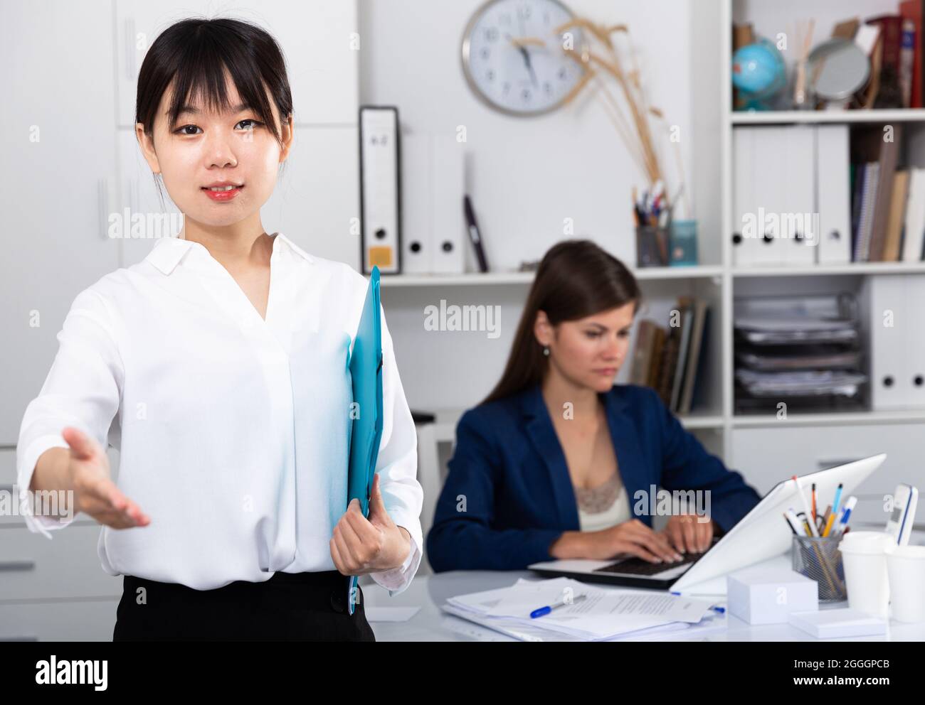 Asian manager greeting guests in office Stock Photo - Alamy
