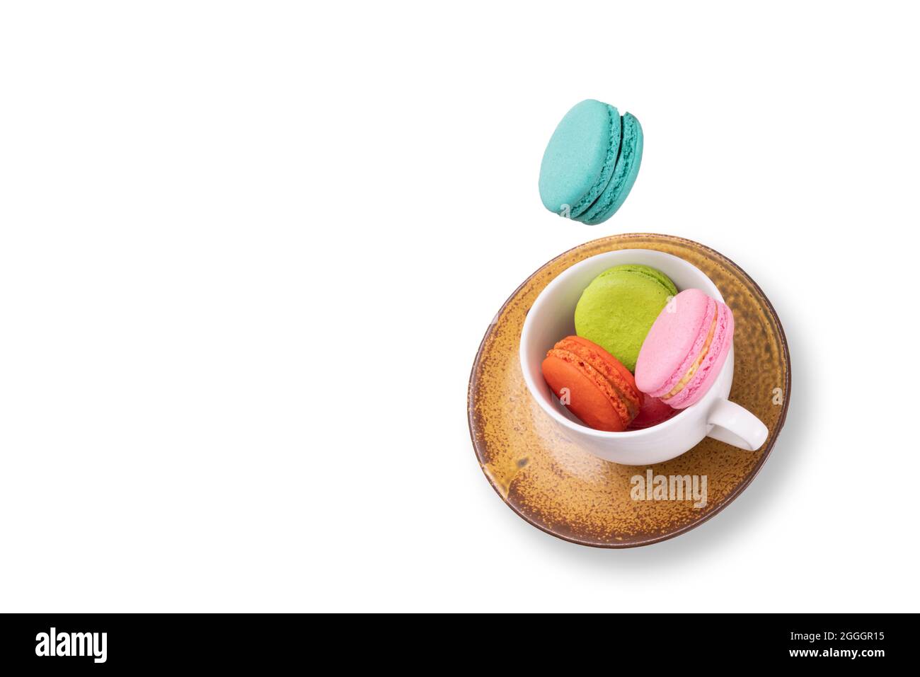 Colorful macaroons  floating on a white tea cup and a orange ceramic plate. Isolation on white back ground. Food levitation concept. Stock Photo