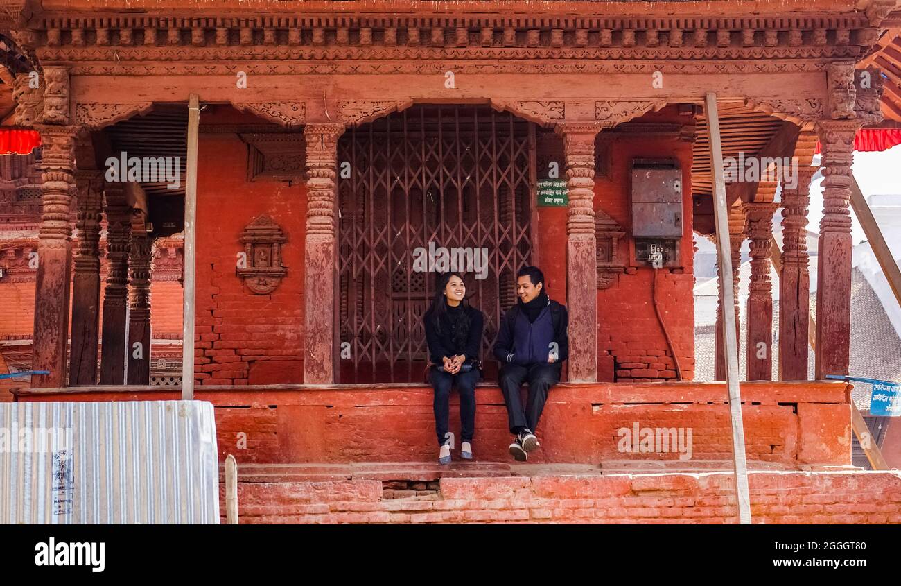Young nepalese couple sitting on the stairs of the Maru Tol North Narayan temple in Kathmandu, Nepal Stock Photo