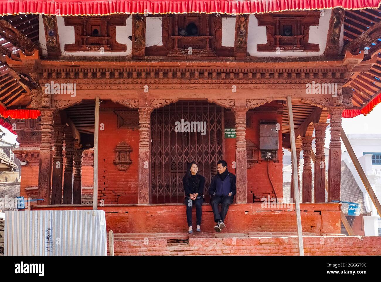 Young nepalese couple sitting on the stairs of the Maru Tol North Narayan temple in Kathmandu, Nepal Stock Photo