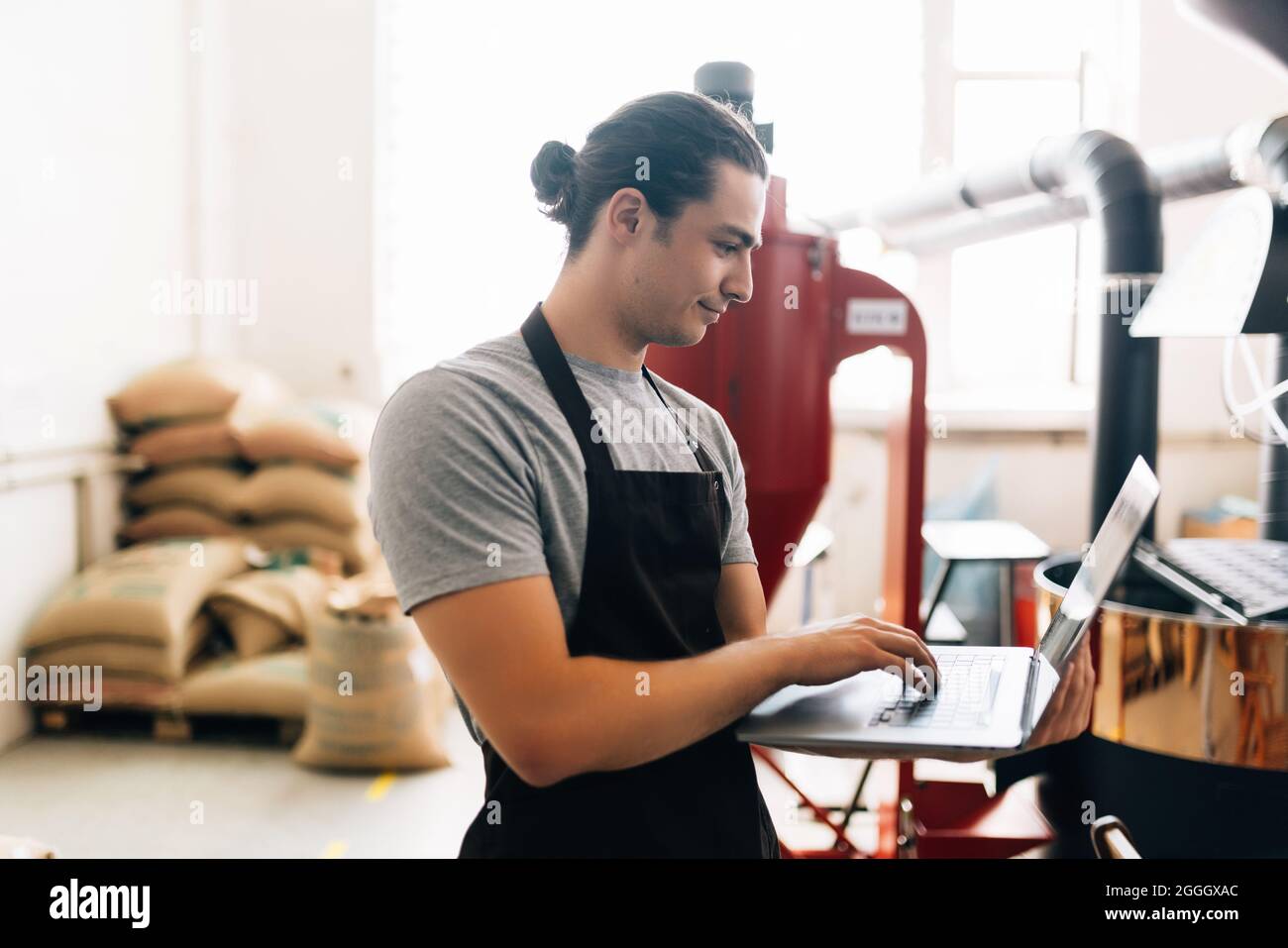 Young man working at coffee production. Barista adjusting coffee ...