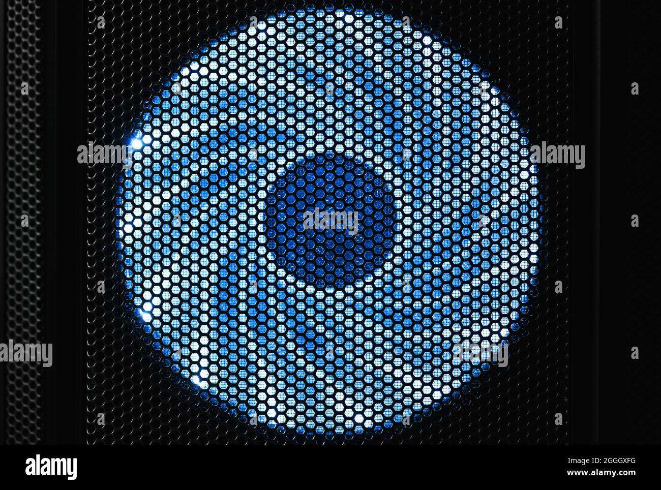 Illuminated by blue LED lights PC cooler fan in dark desktop case, front view Stock Photo