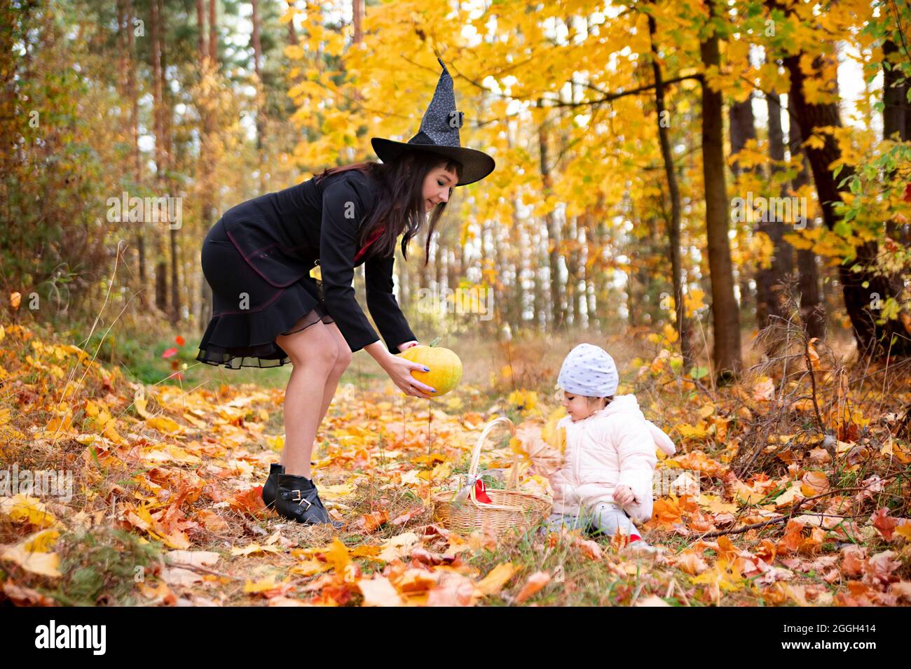 black witch woman with little toddler bunny in the autumn forest. halloween celebration, costume party. Stock Photo