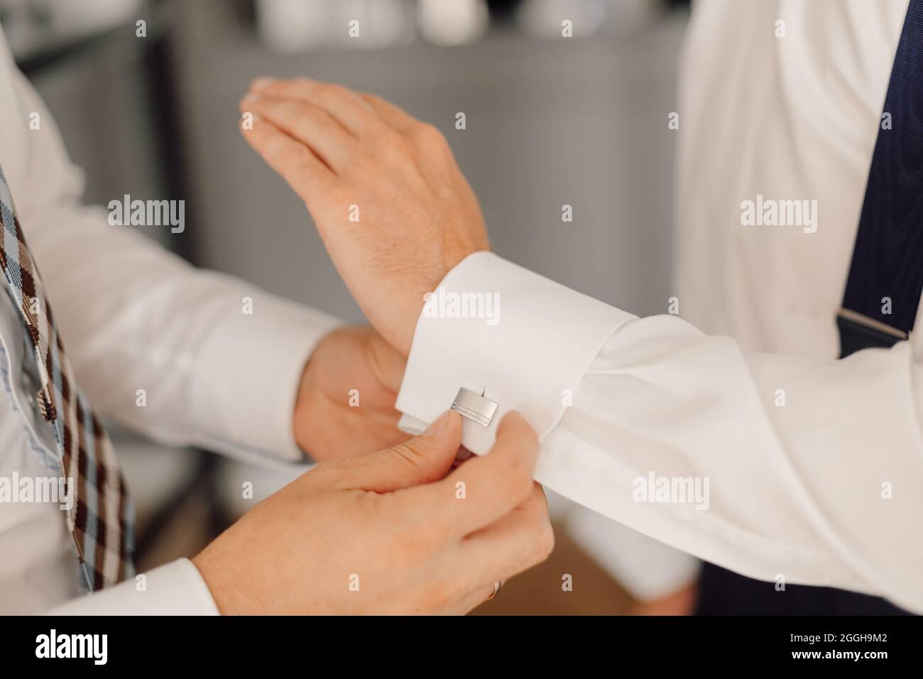Wedding day of young man, button up cufflinks on white shirt. Elegance and business style concept. Stock Photo
