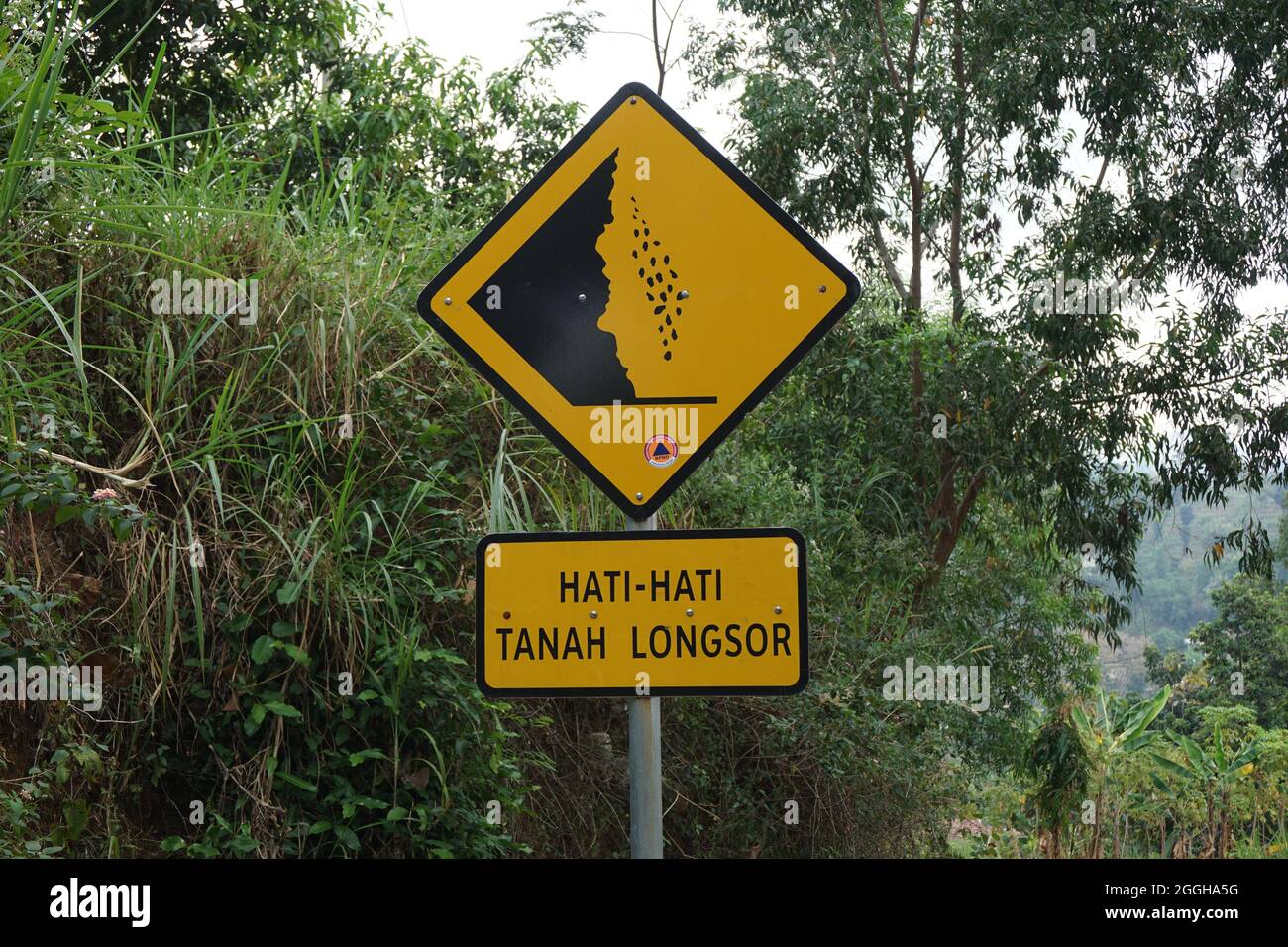 Yellow sign with a natural background. Hati-hati tanah longsor means ...