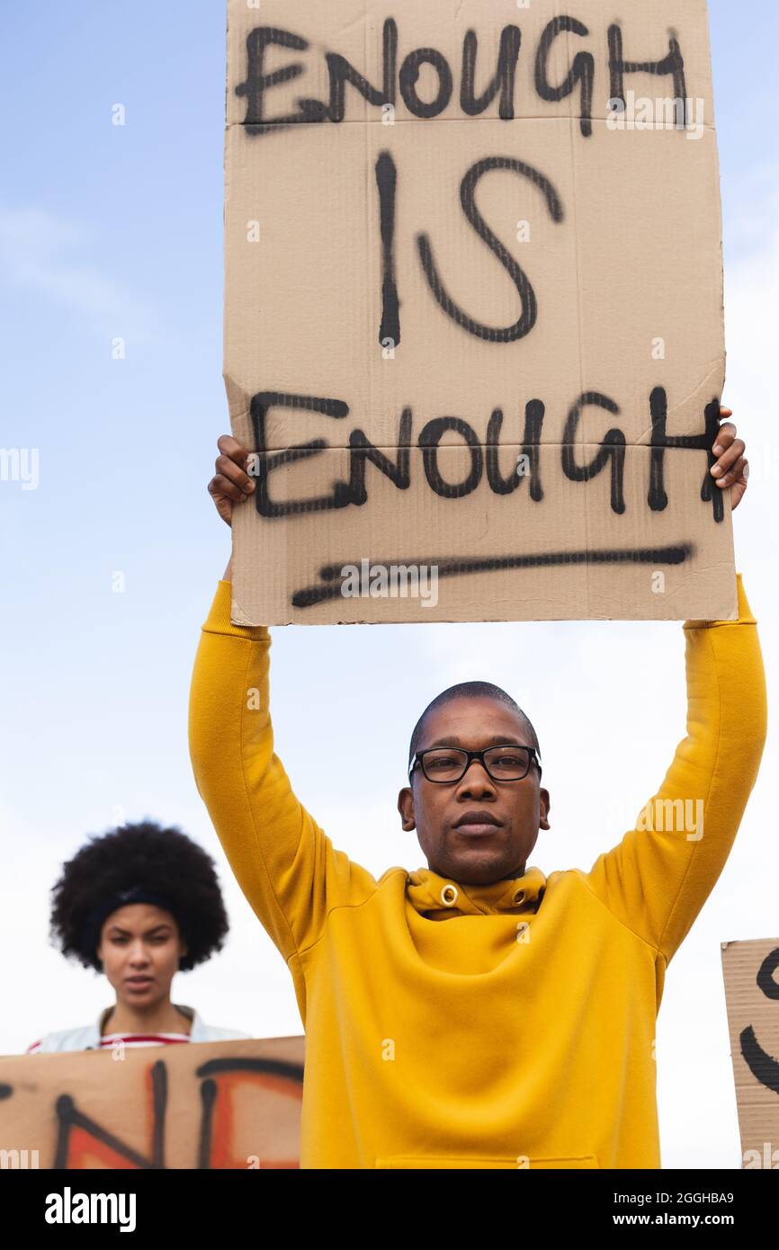 African american man holding placard saying enough is enough at protest march Stock Photo
