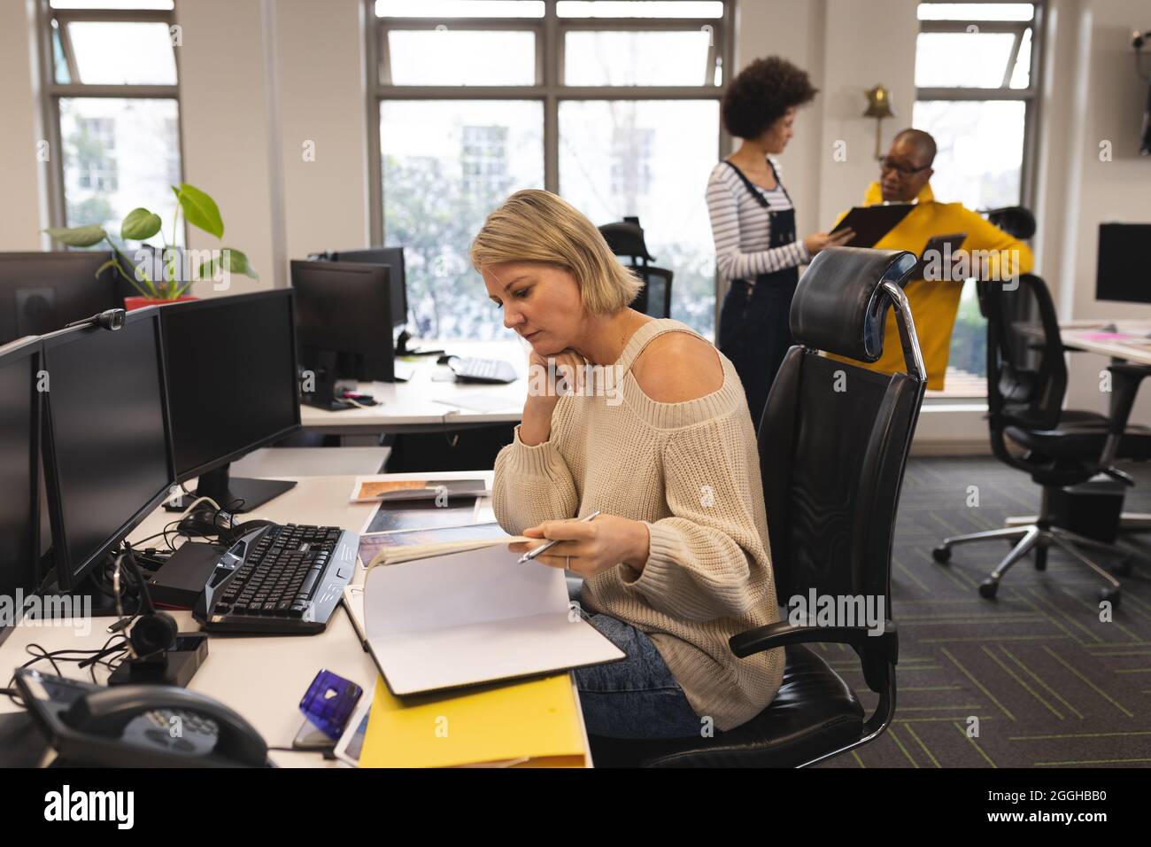 Caucasian female creative at work, sitting at desk, taking notes Stock Photo