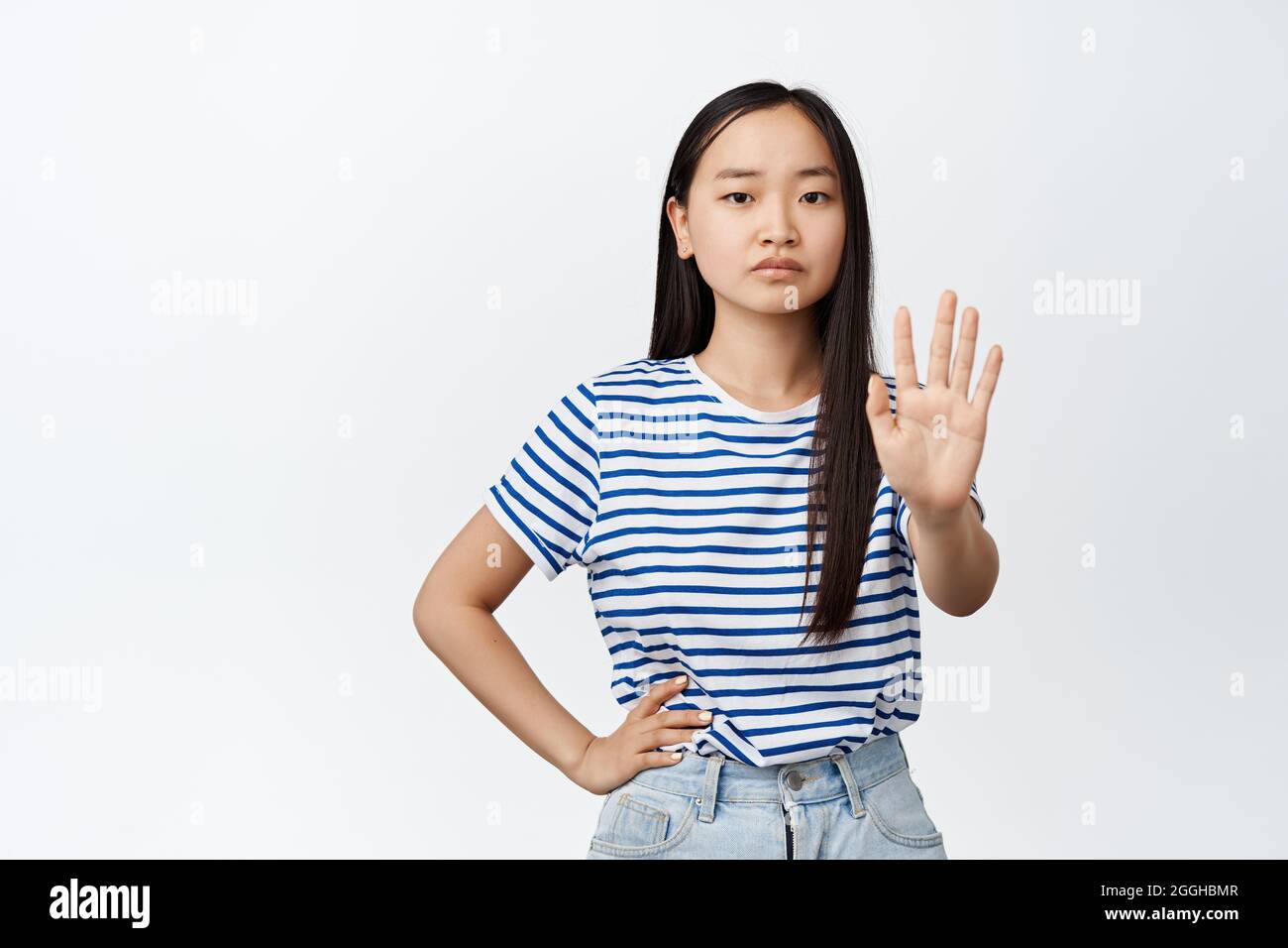 Asian woman say no. Teen girl extend one hand, taboo refusing gesture, stop  sign, frowning and looking serious at camera, white background Stock Photo  - Alamy