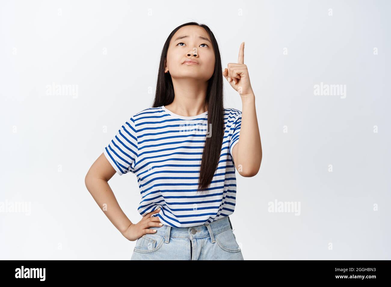 Unsure young asian woman pointing and looking up with troubled