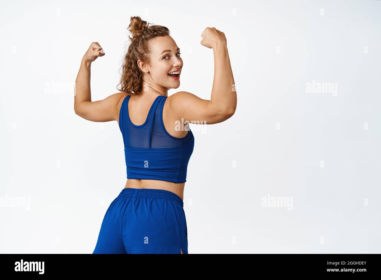 Healthy and active sportswoman showing muscles, turn behind and
