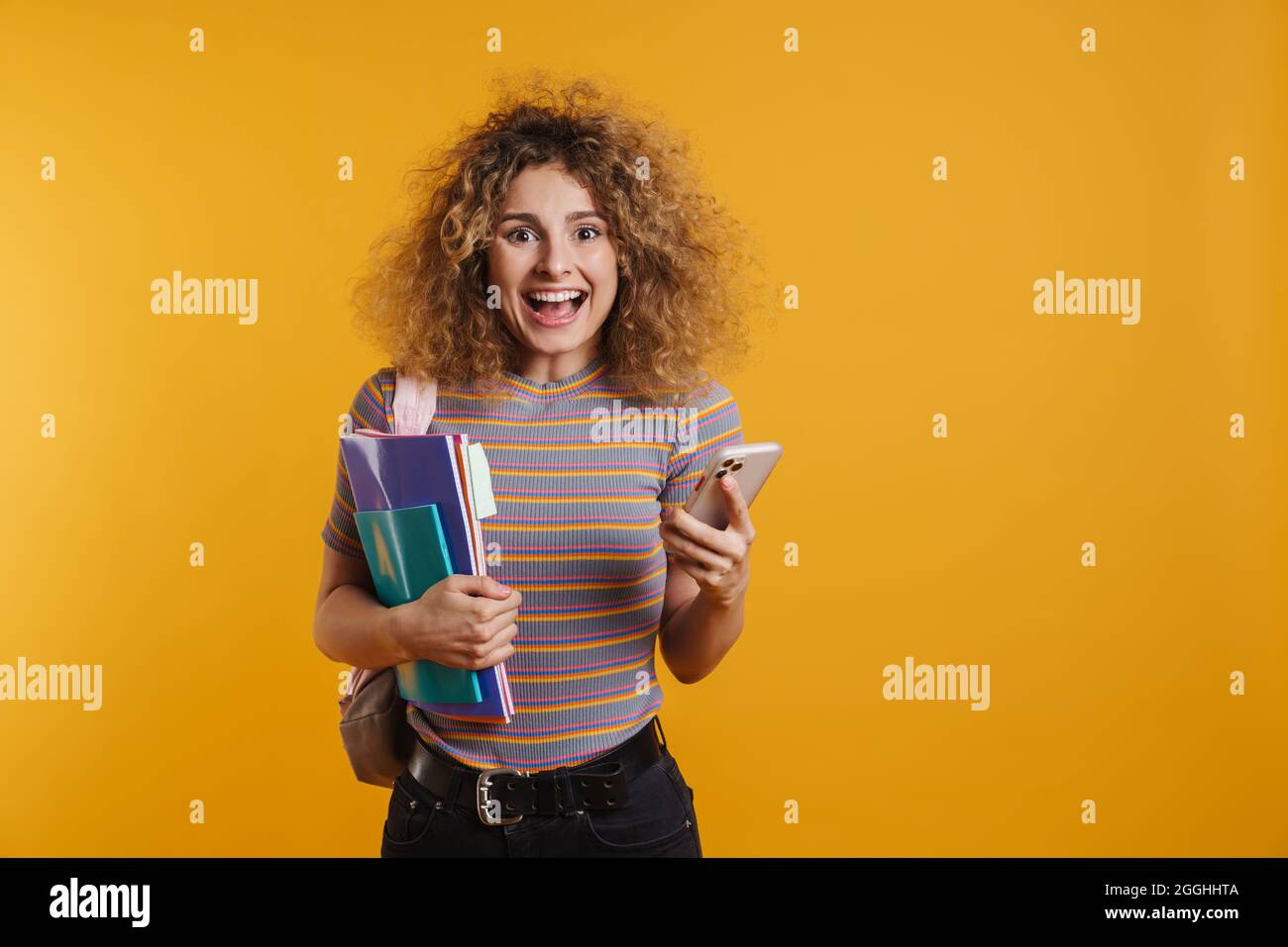 Happy young woman student with backpack standing holding textbooks and ...