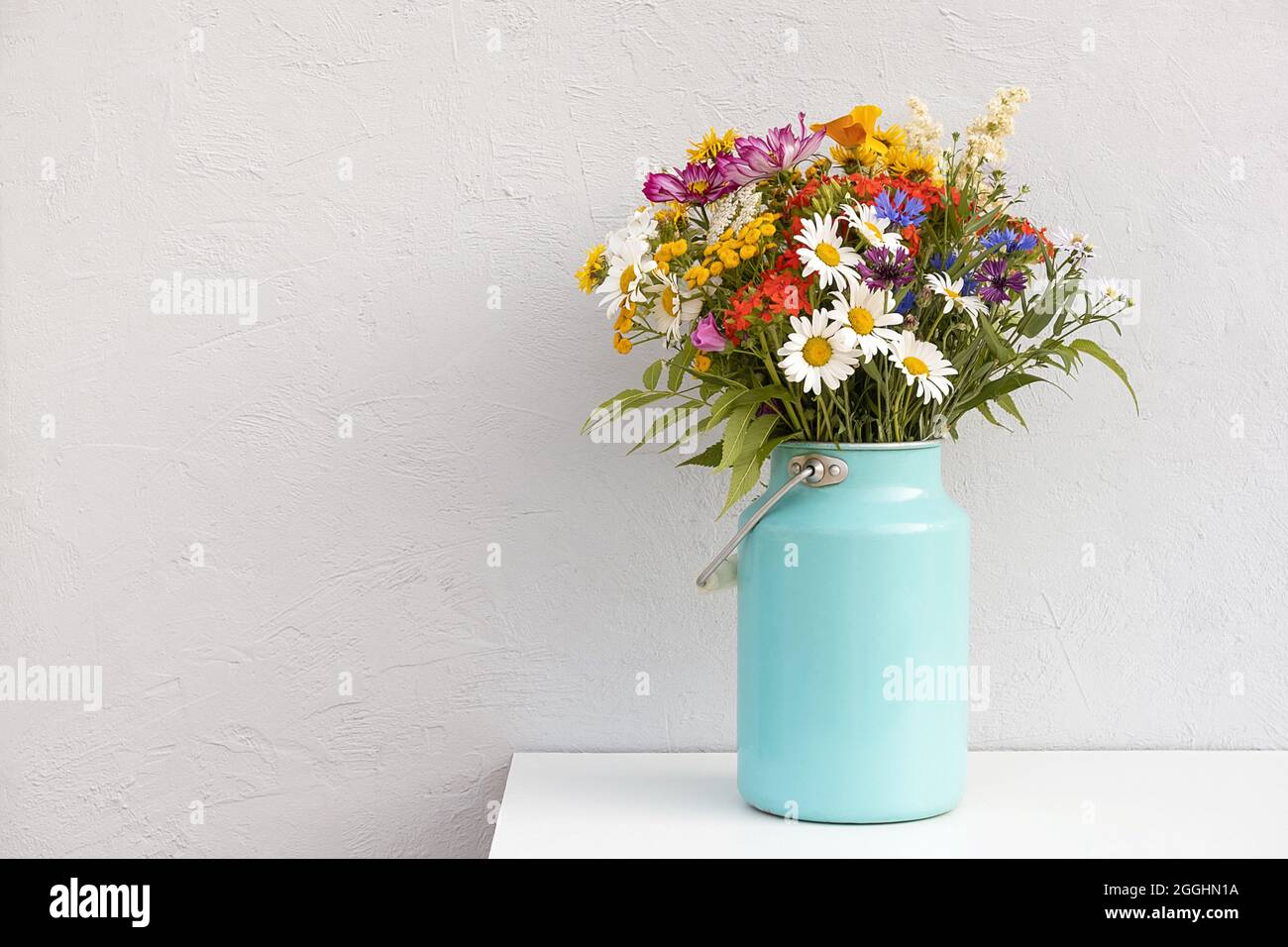 Bouquet of bright flowers in tin can vase on background grey stone wall. Template for postcard. Concept Women's day, Mothers Day, Hello summer or Hell Stock Photo