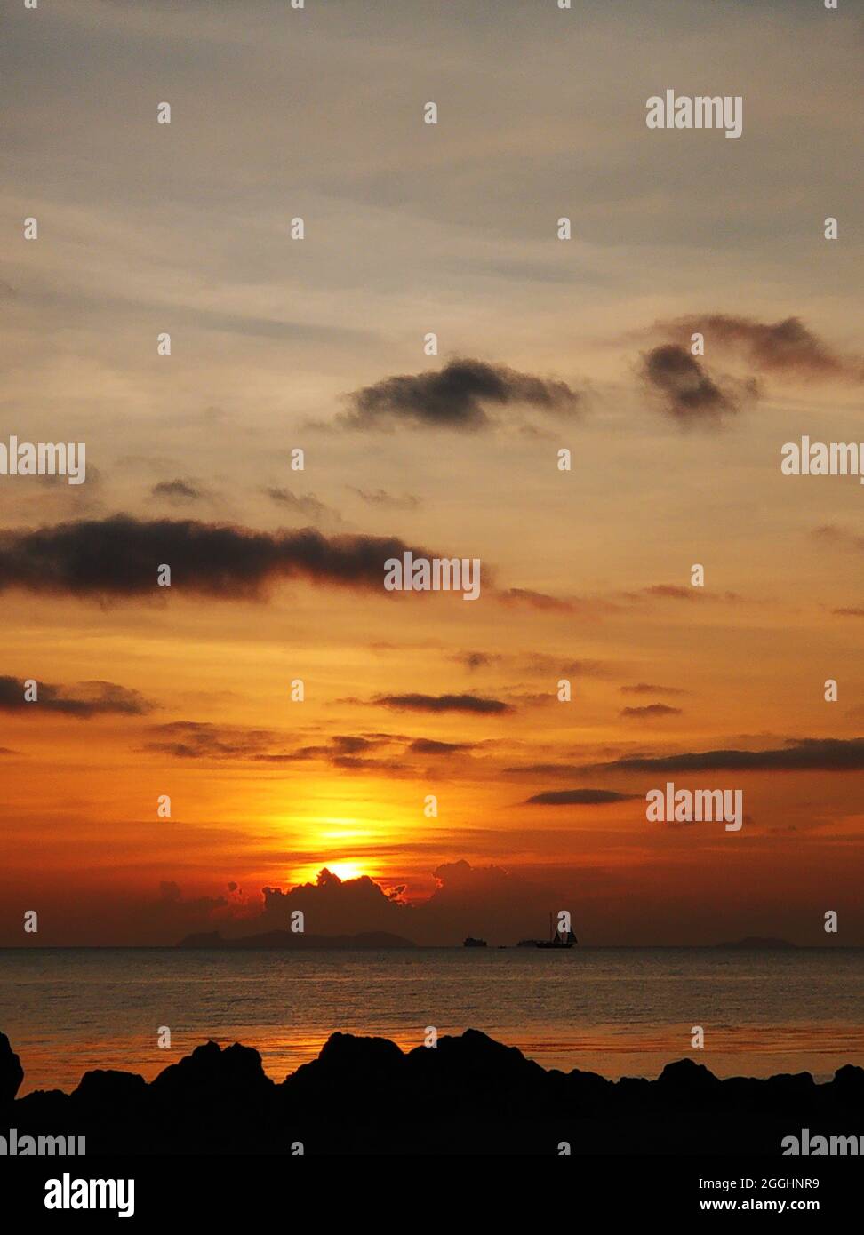 Fiery sunset with clouds by the ocean Stock Photo - Alamy