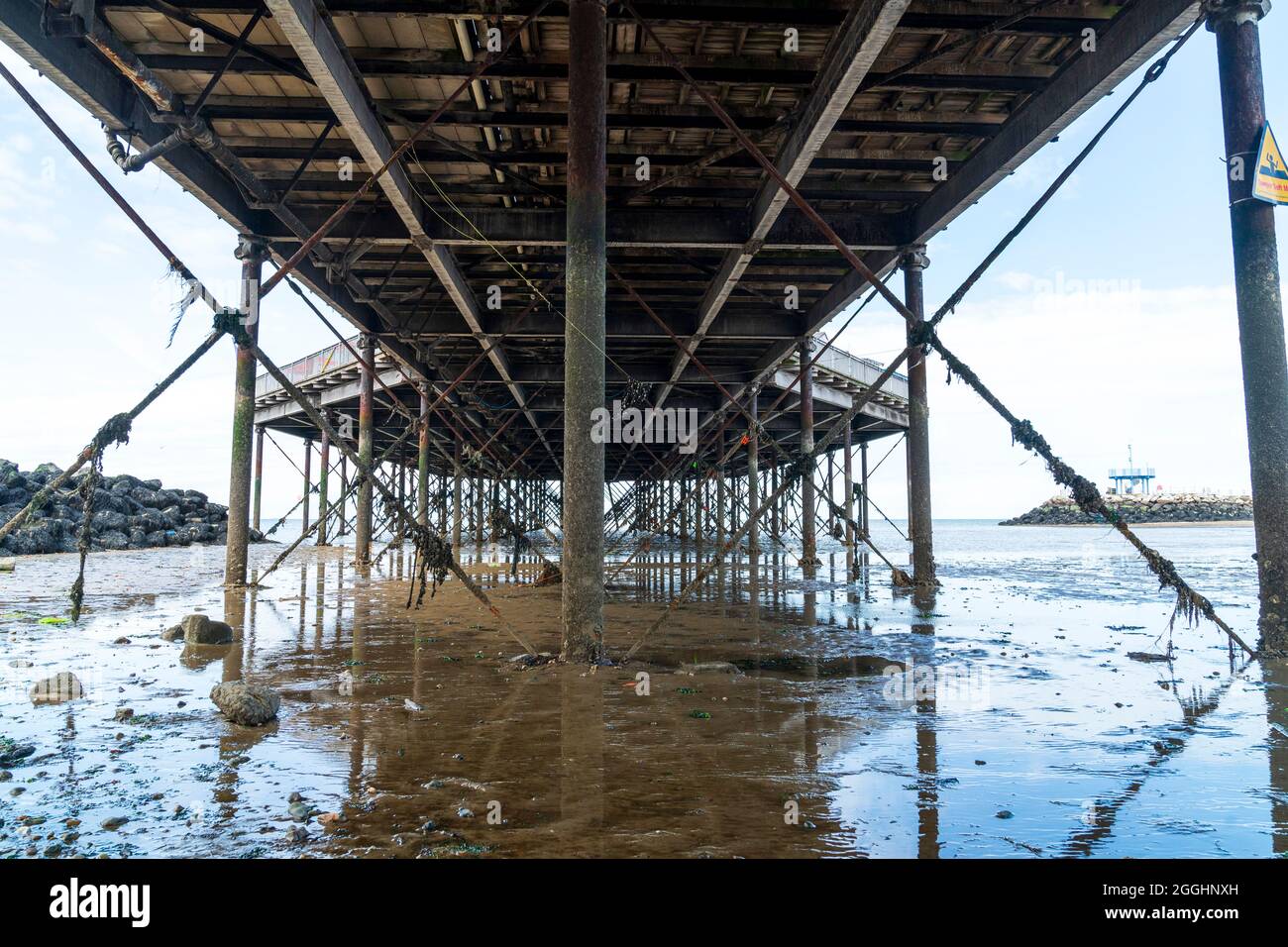 Underside of Herne Bay pier, England. A good example of a Victorian wood and iron pier. View along from beach showing struts and supports at low tide. Stock Photo