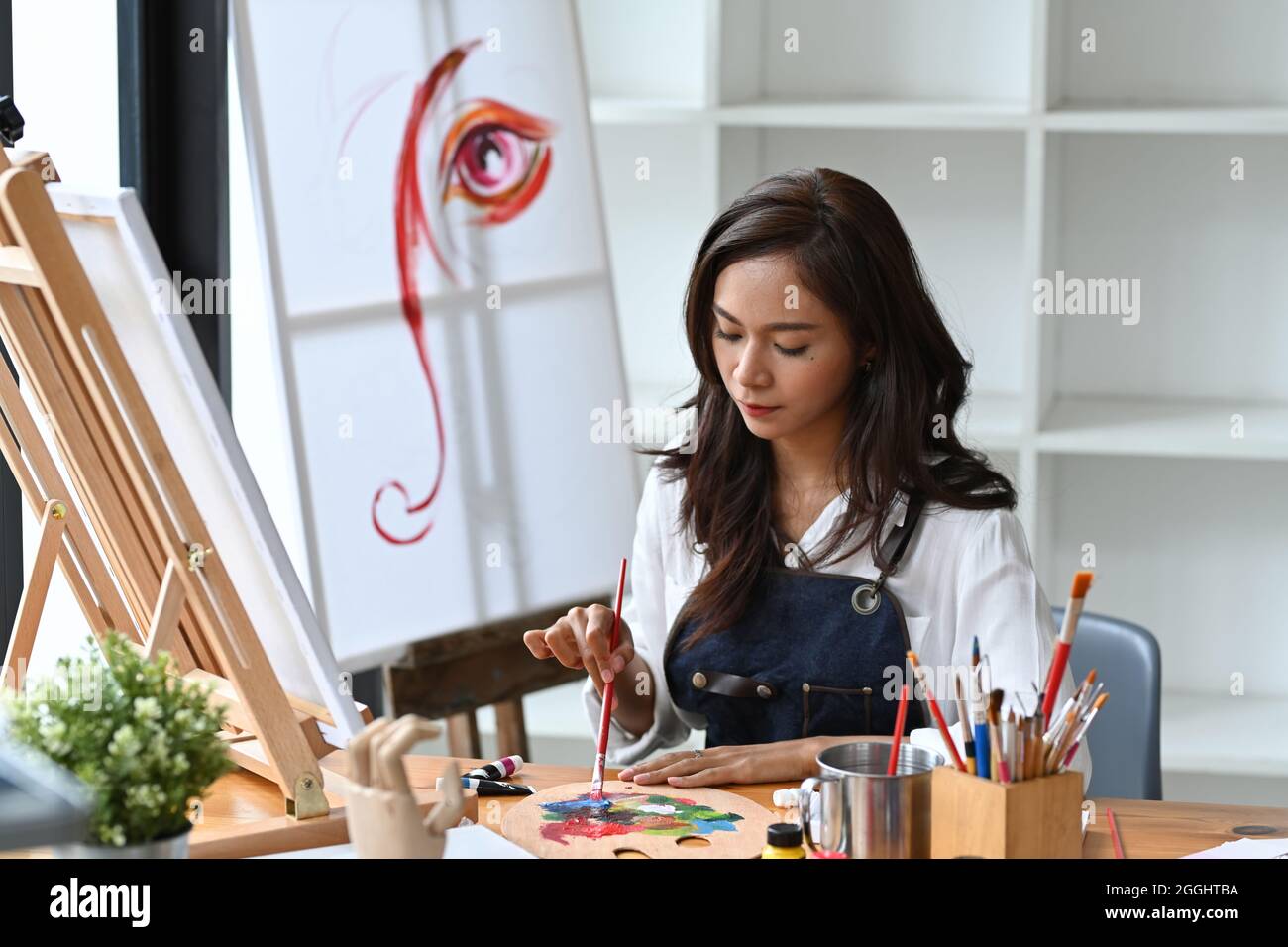 Beautiful female artist holding brush and mixing color oil painting on ...