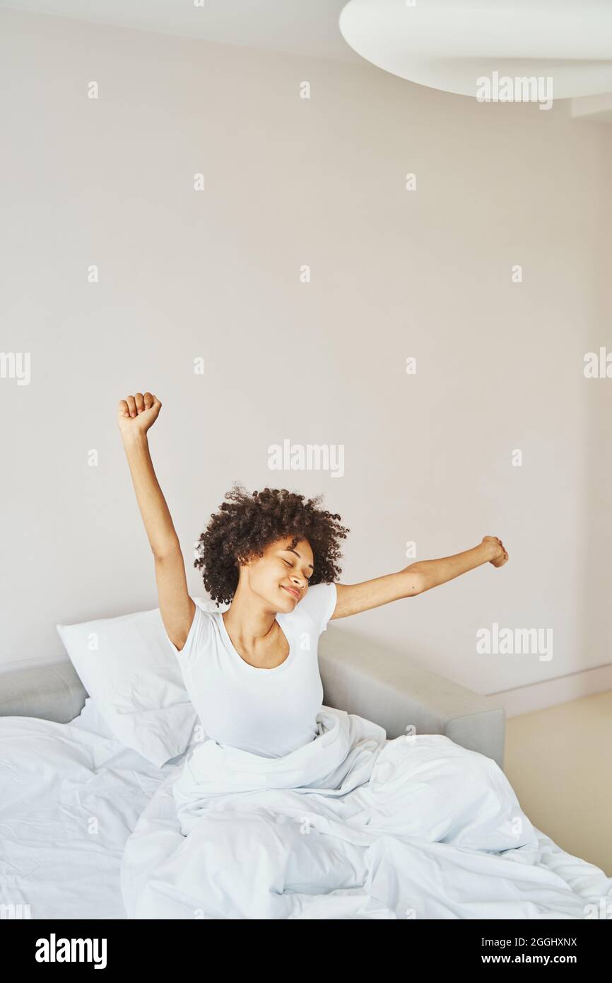 Pleased lady having a stretch after wake-up Stock Photo