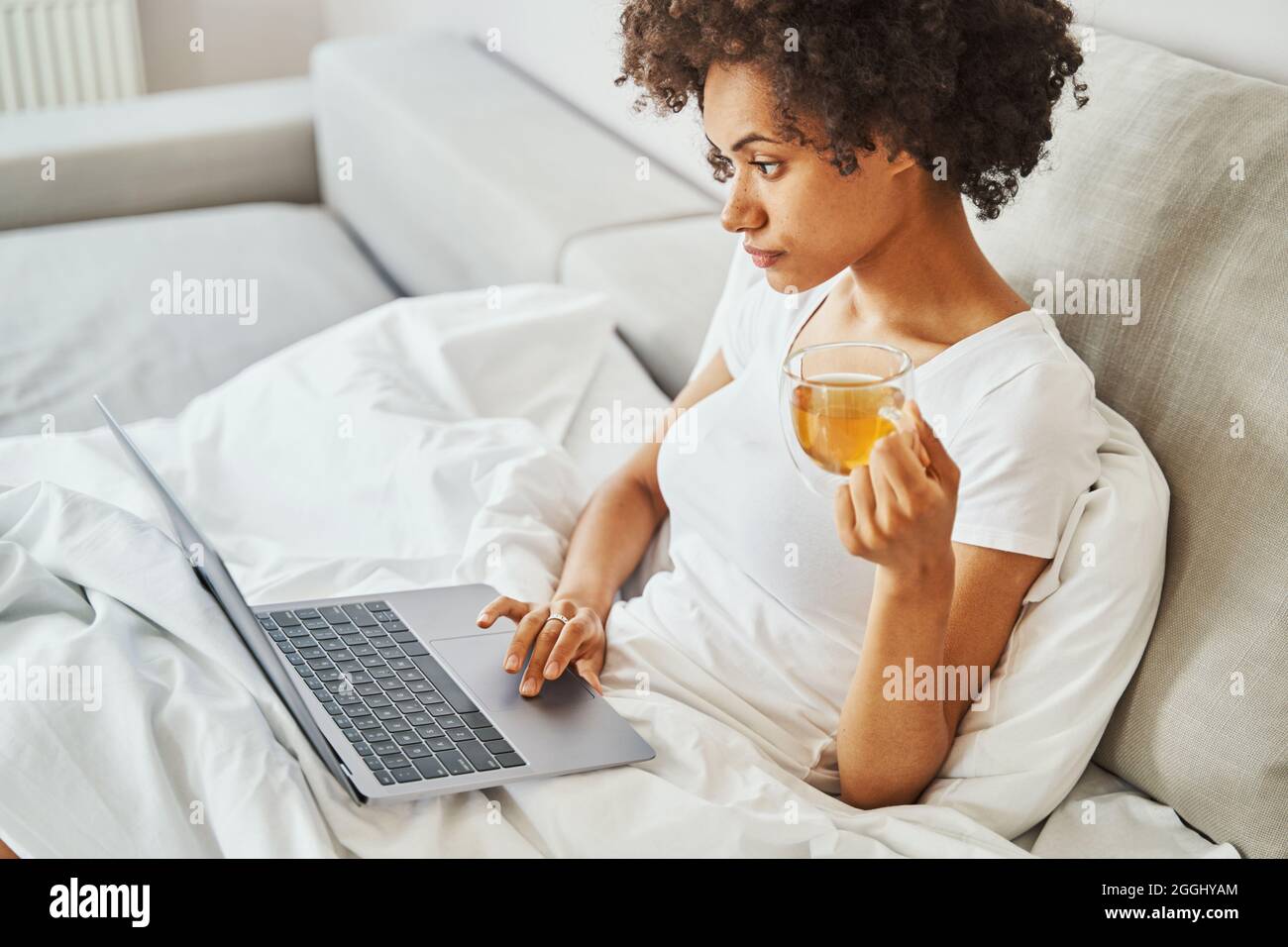 Young woman using her portable personal computer in bed Stock Photo