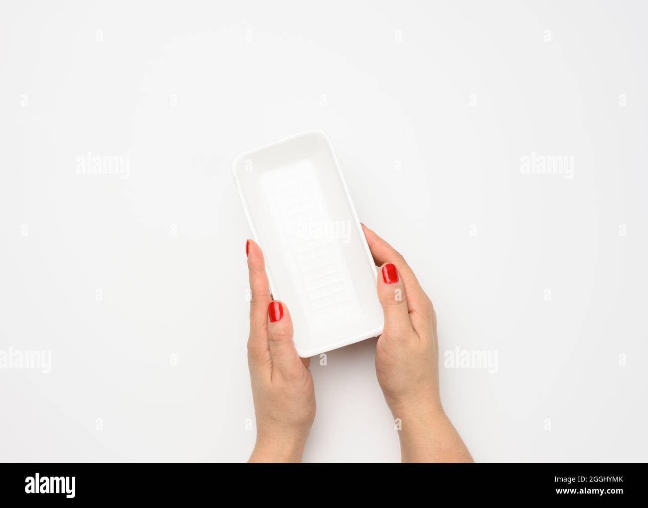 Female hands hold an empty rectangular disposable plastic container on a white background, top view Stock Photo
