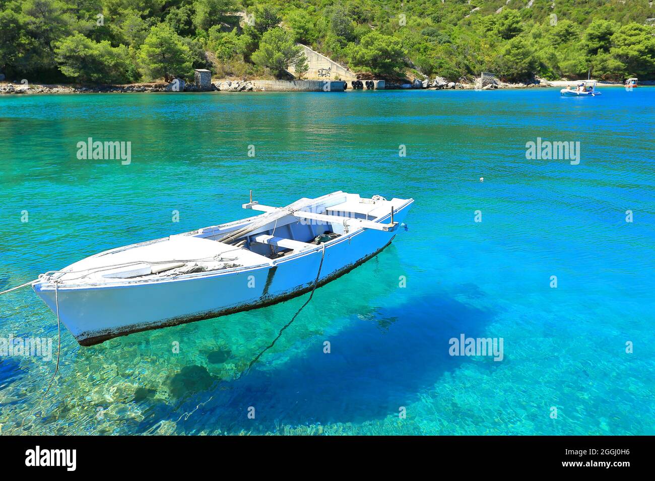 Old wooden boat on surface of clear blue sea Stock Photo - Alamy