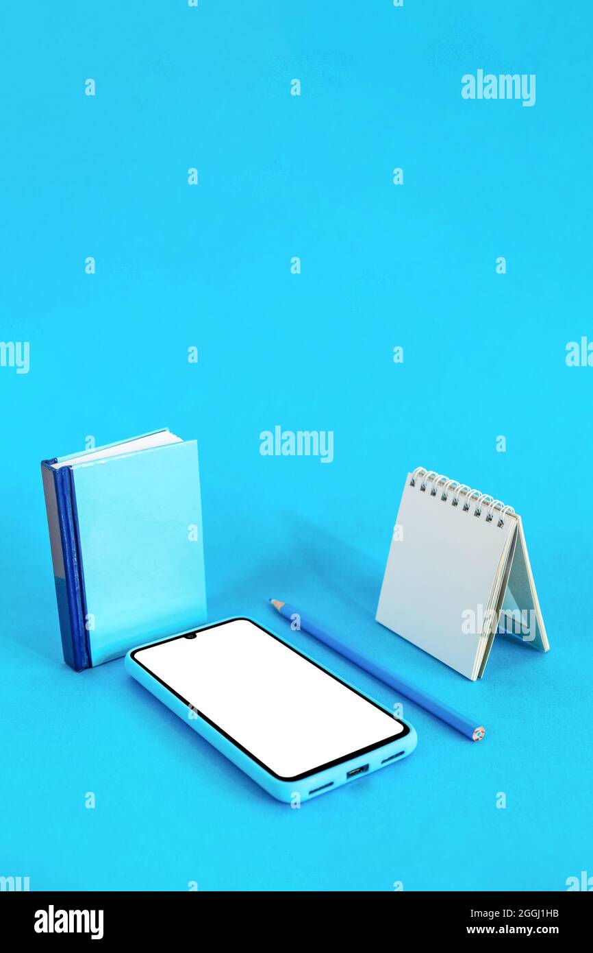 Book, pencil, notebook, and smartphone isolated on blue background with copy space Stock Photo