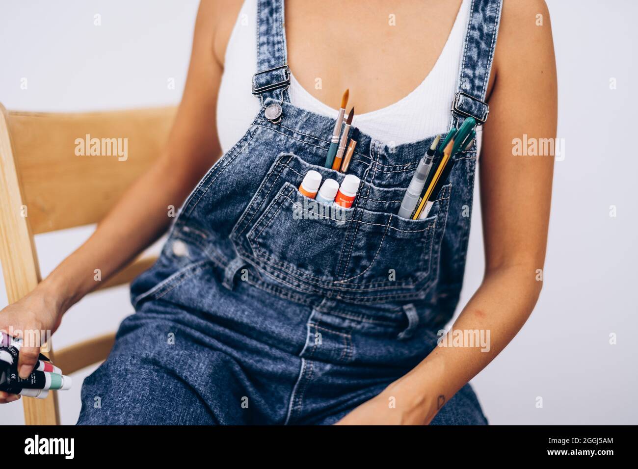 Brushes and paints in the pocket of denim overalls Stock Photo