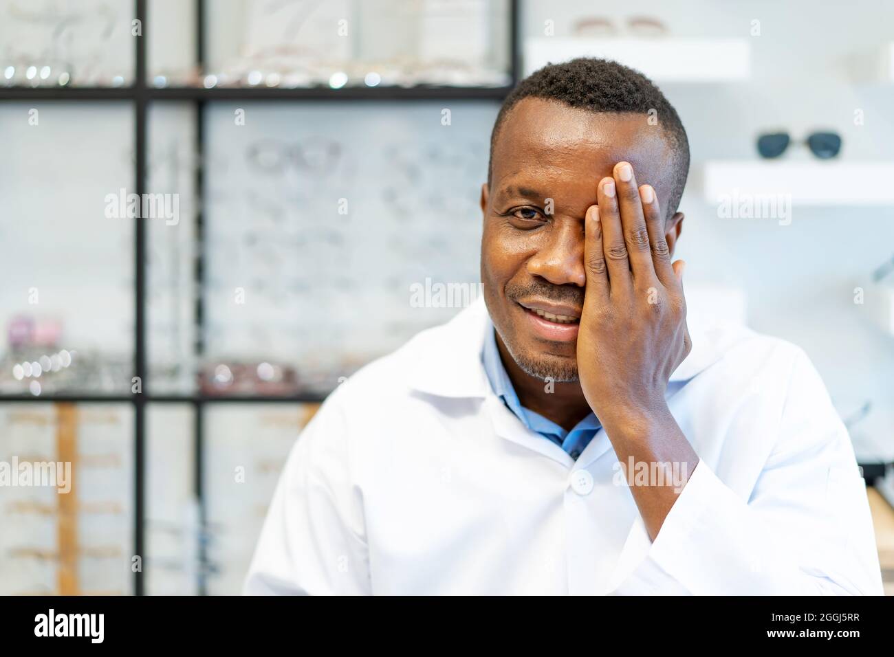 Optician covering one eye with palm as if having his eyes tested during vision examination Stock