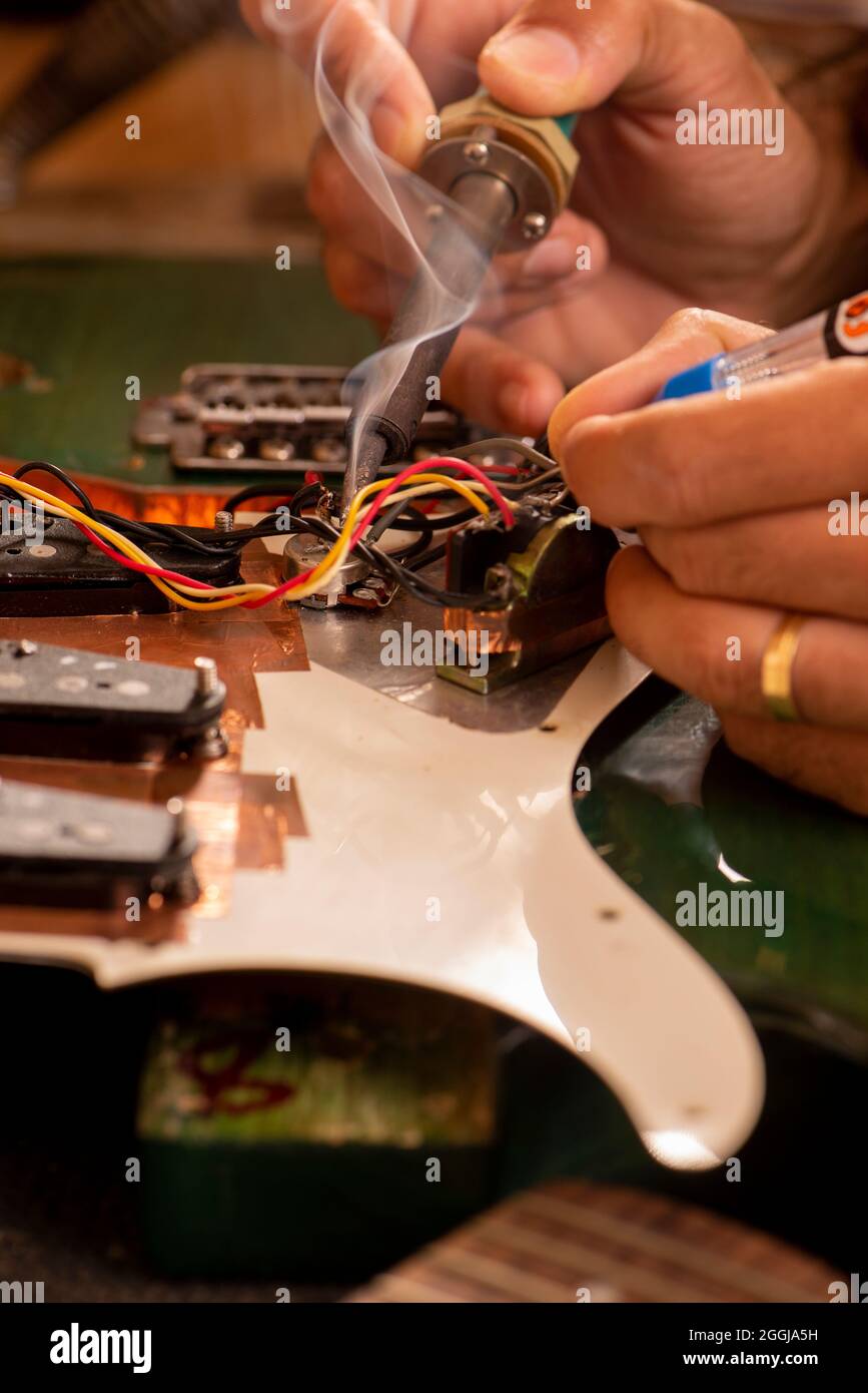 man's hands soldering a electric guitar wire in his Stock