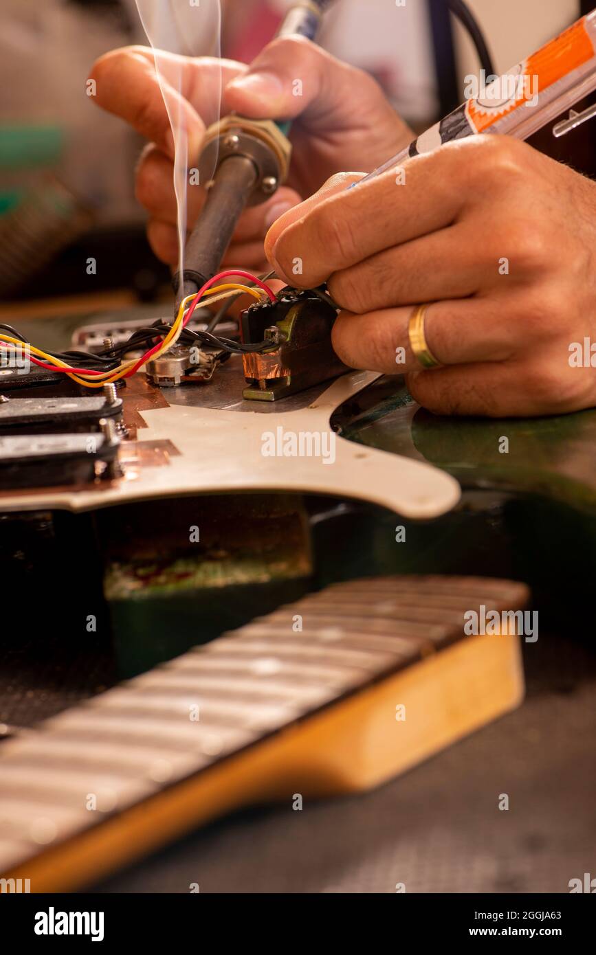 man's hands soldering a electric guitar wire in his Stock