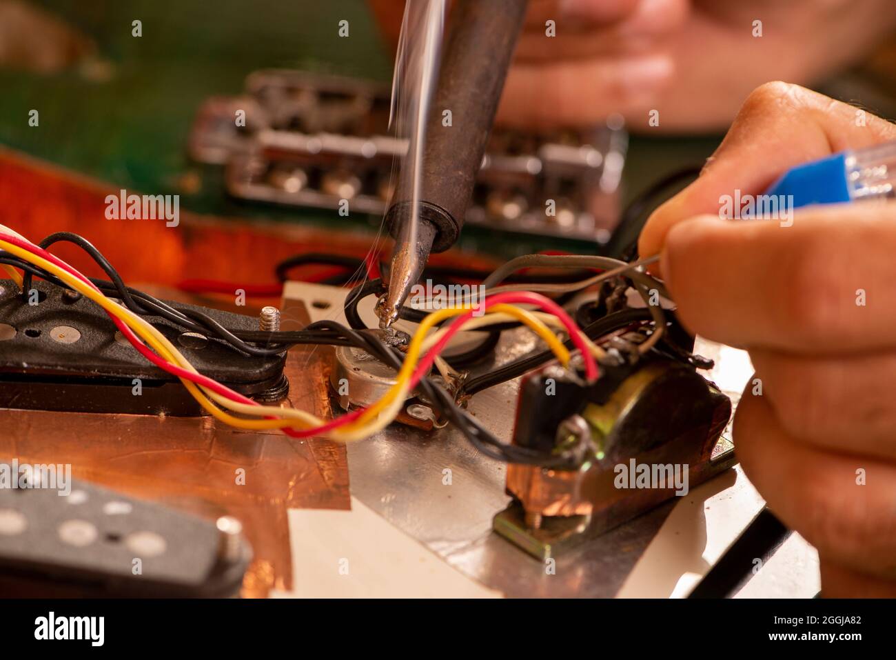 man's hands soldering a electric guitar wire in his Stock