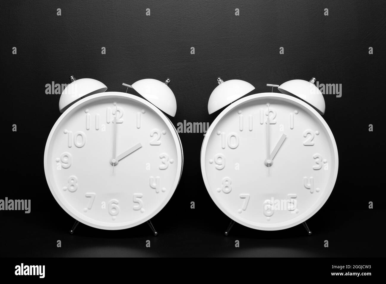 Daylight saving time concept. Two White Retro clock isolated on black background. Copy space Stock Photo
