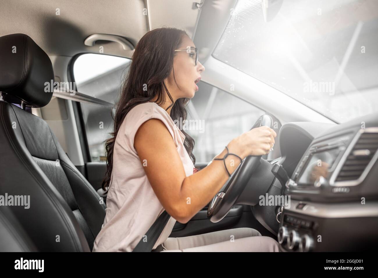 Inexperienced female driver sits behind the steering wheel very close