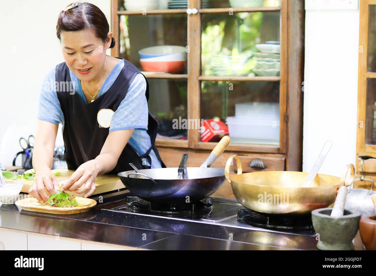 Asian woman wearing apron, cooking in kitchen Stock Photo Alamy