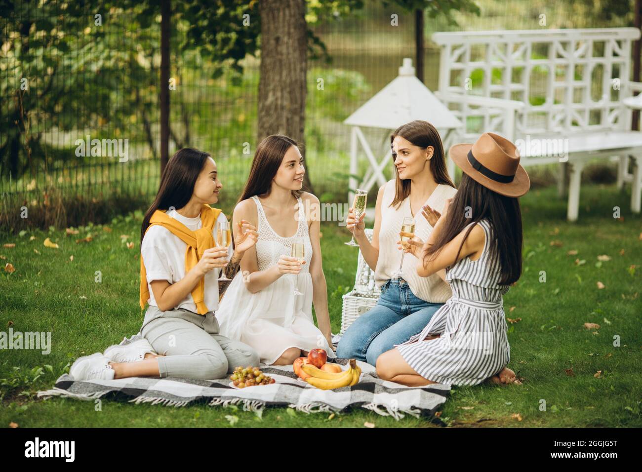 Four Beautiful Young Girls Sitting On Grass And Having Picnic Stock