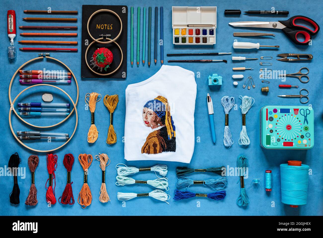FROSINONE, ITALY - Aug 01, 2021: An embroidered portrait of the girl with the pearl earring with embroidery tools and threads on a blue surface Stock Photo