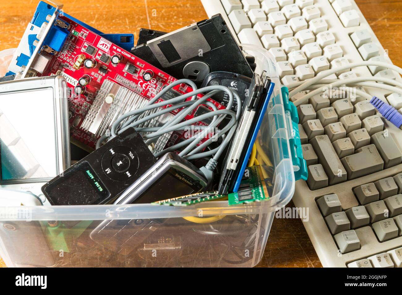 Computer keyboards and obsolete electronic and technological objects in a plastic box. Technological waste and its recycling is one of the issues to b Stock Photo
