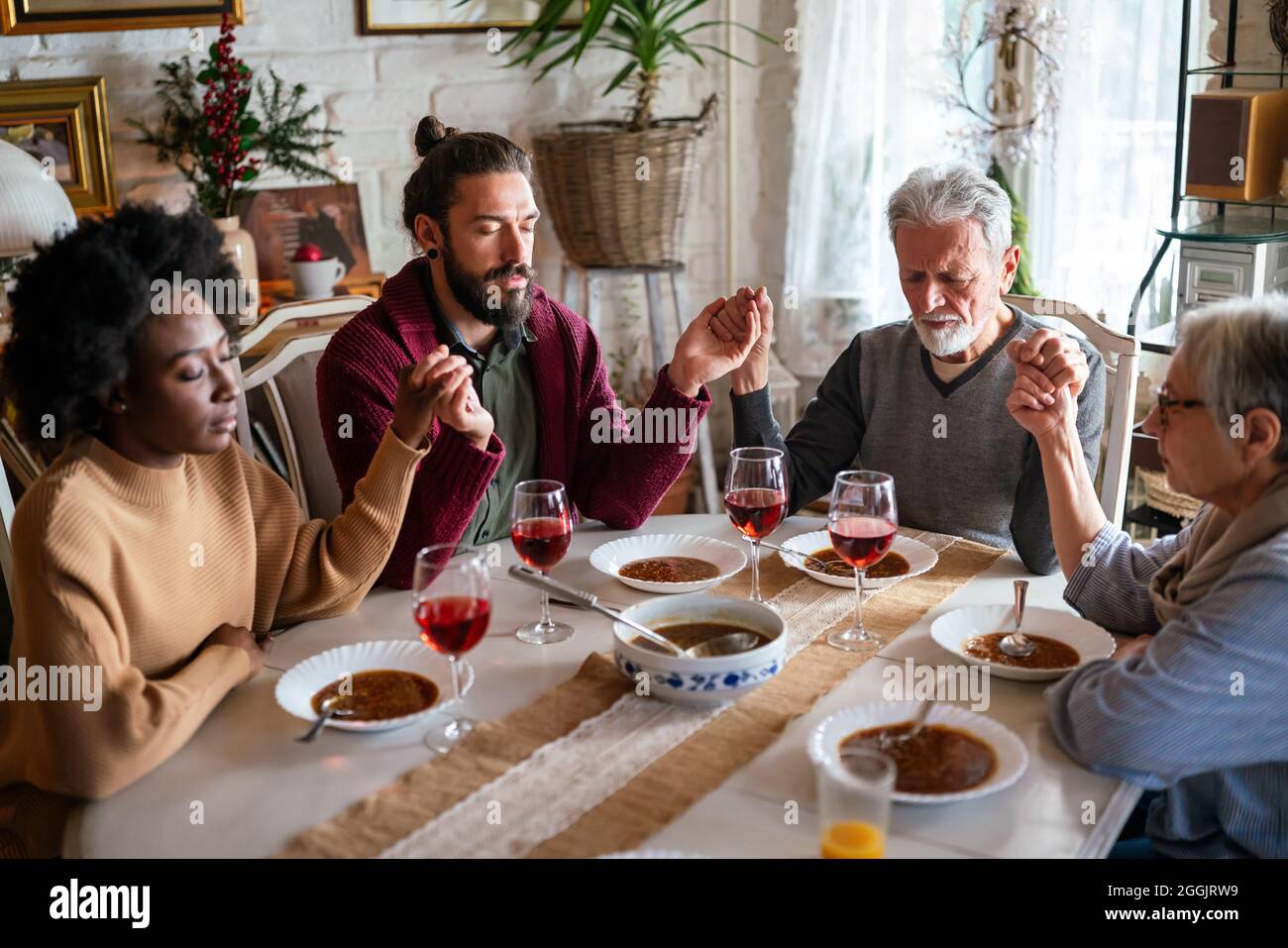 Family and religious concept. Group of multiethnic people with food praying before meal Stock Photo