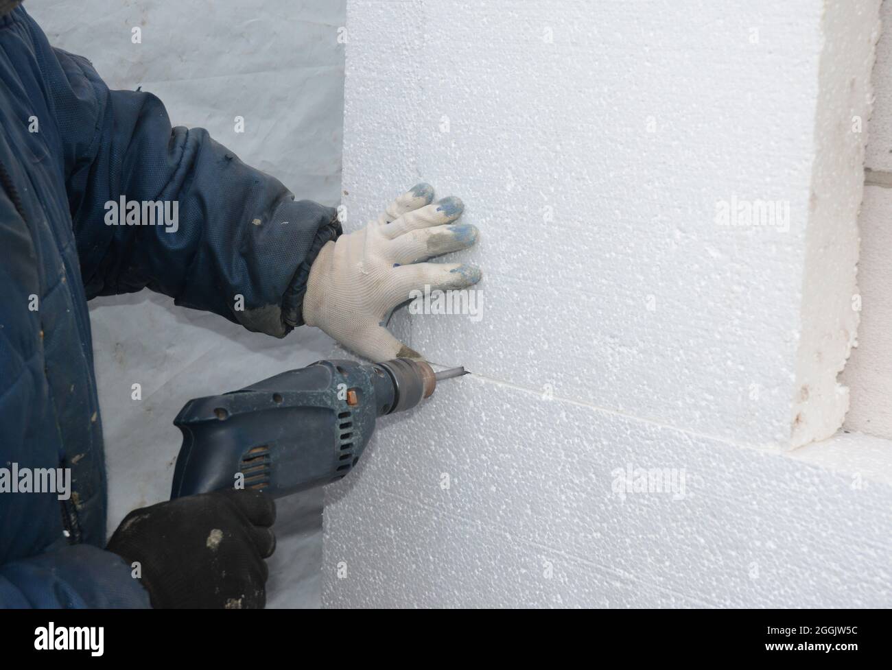 Builder drilling wall for installing anchors to hold rigid insulation