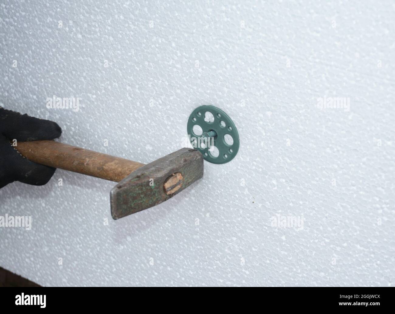 Insulation of the house with polyfoam. The worker is installing a styrofoam  board on the facade Stock Photo - Alamy