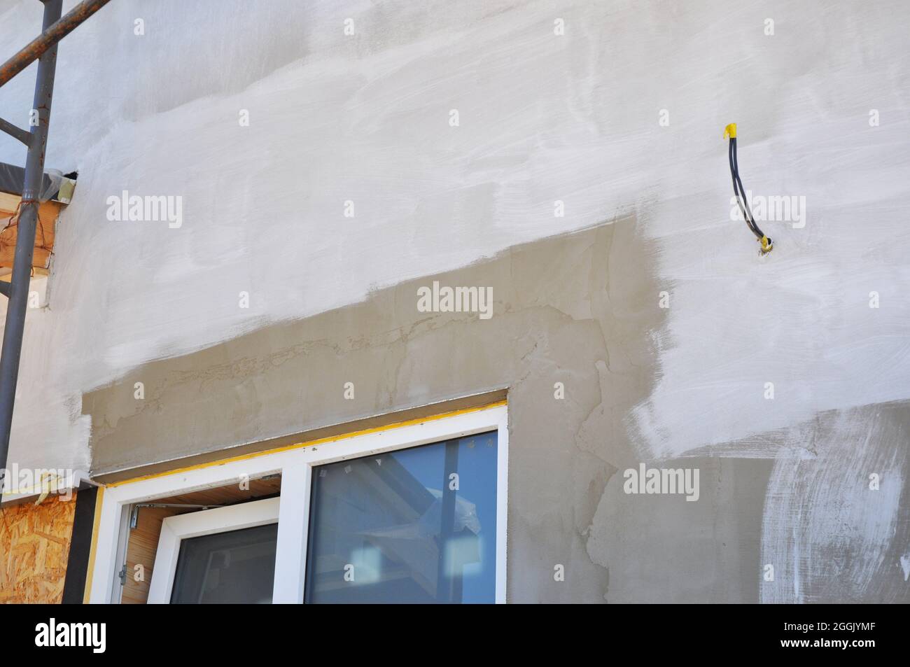 Painting house wall after plastering and stucco. Window insulation. Unfinished painting on house