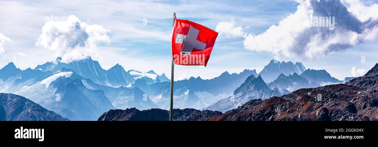 Swiss flag in front of alpine panorama in the high mountains Stock Photo