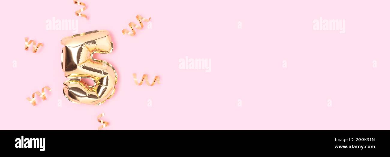 Banner with number 5 golden air balloon with confetti on a pink pastel background. Stock Photo