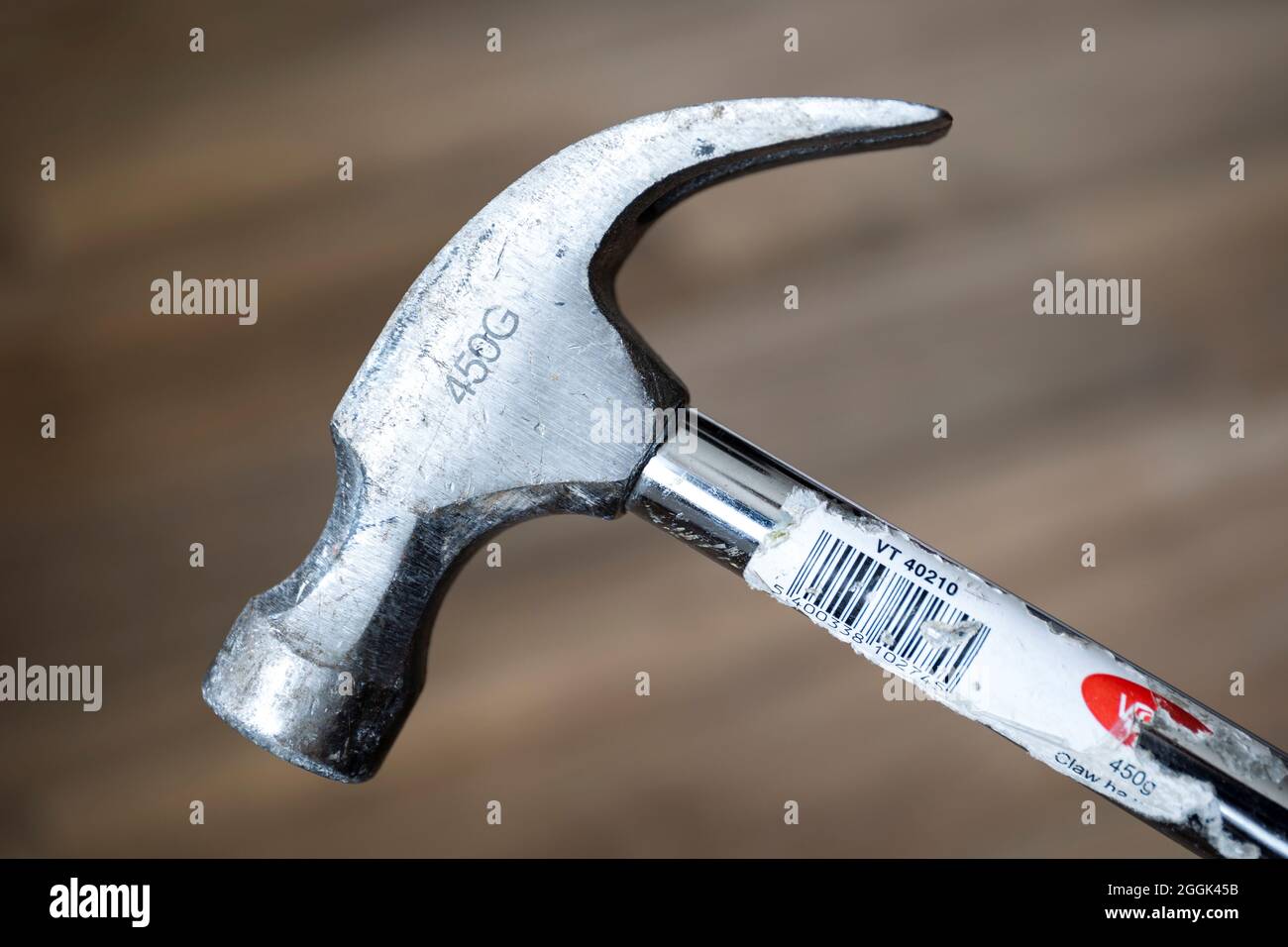 A sideways portrait of a metal claw hamer of 450 grams. The neck, eye, claw, face and head parts of the worn manual construction ool are clearly visib Stock Photo