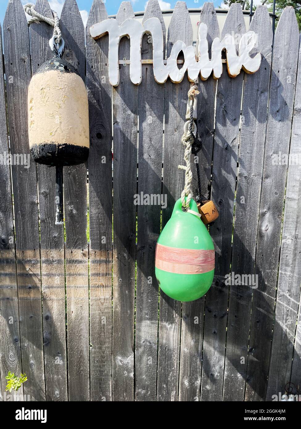 Old, weathered wooden fence with signs & buoys at Perry’s Lobster Shack is a Low-key waterside shack offering lobster & seafood plates. Stock Photo