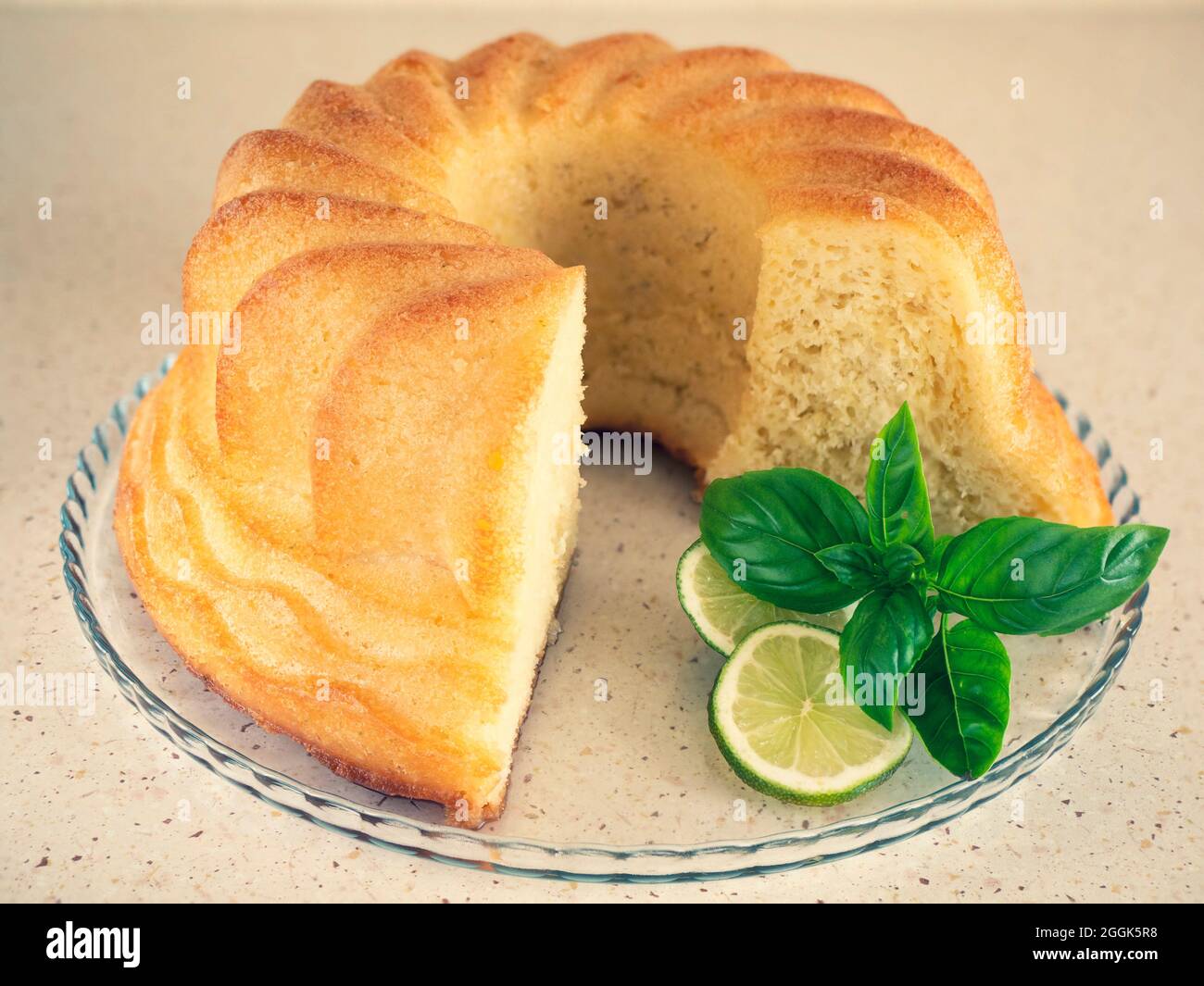 Rum baba on the glass plate with lime and basil. Homemade round yeast cake. Italian dessert Stock Photo