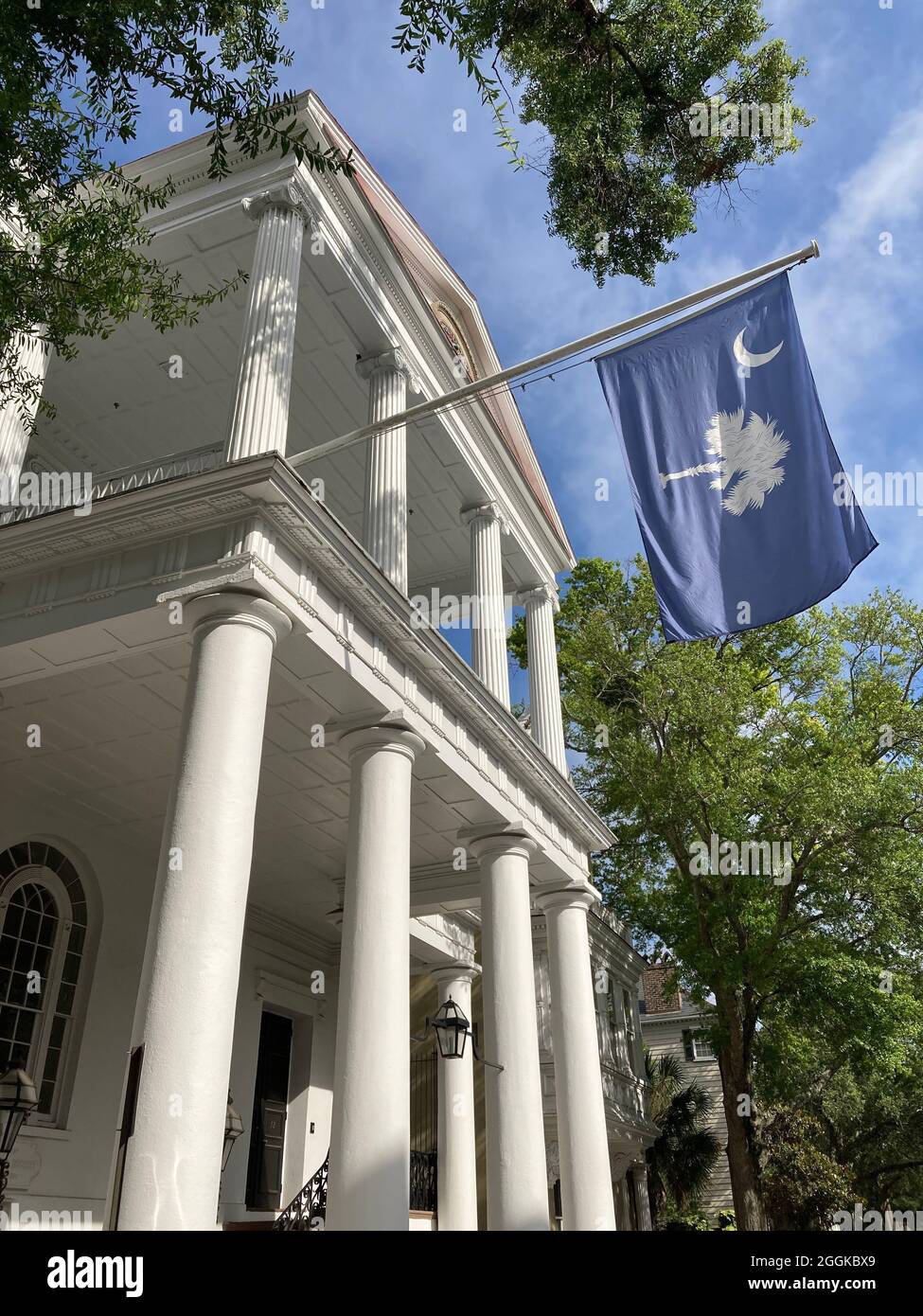Colonial home in Charleston, South Carolina, with flag of South Carolina. Flag consists of white palmetto tree and white crescent. Stock Photo