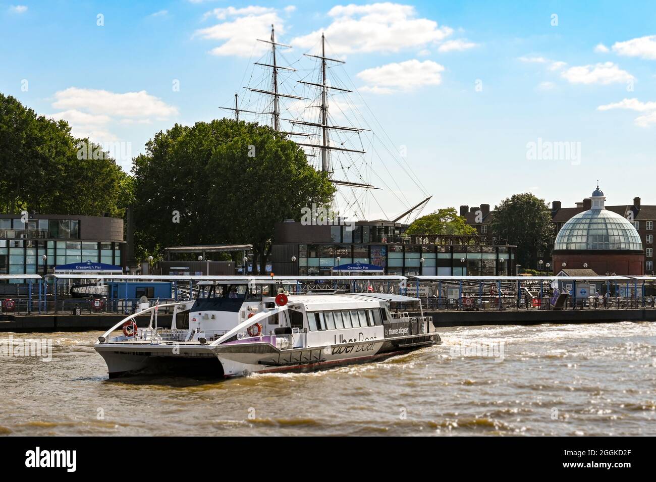 London, England - August 2021: Thames Clipper water taxi on the River Thames leaving Greenwich pier. Stock Photo