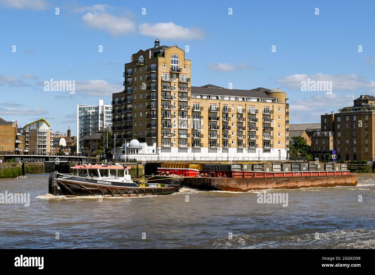 London, England - August 2021: Industrial tugboat towing a large barge with containers on the River Thames. Stock Photo