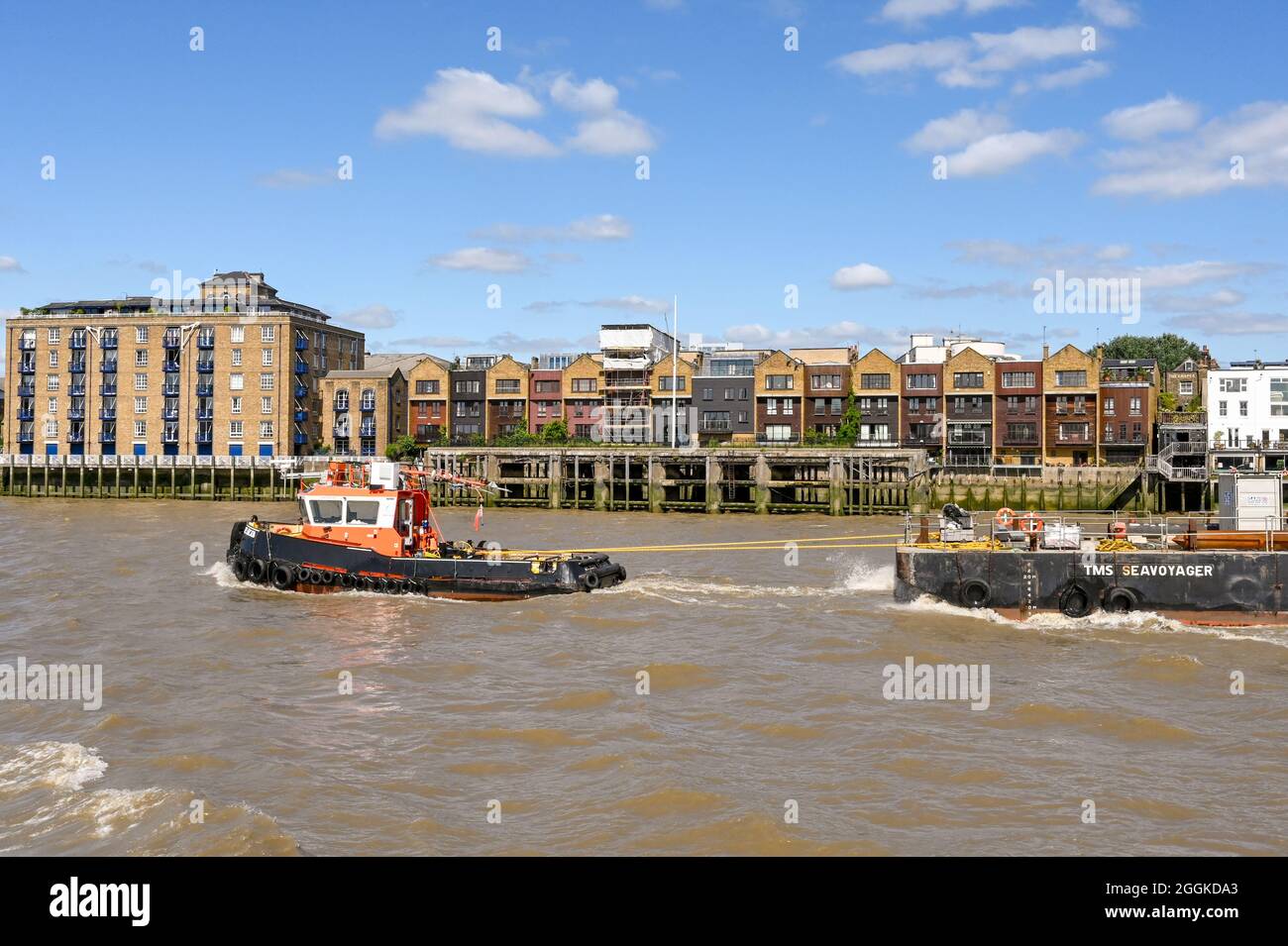 London, England - August 2021: Industrial tugboat towing a barge on the River Thames Stock Photo