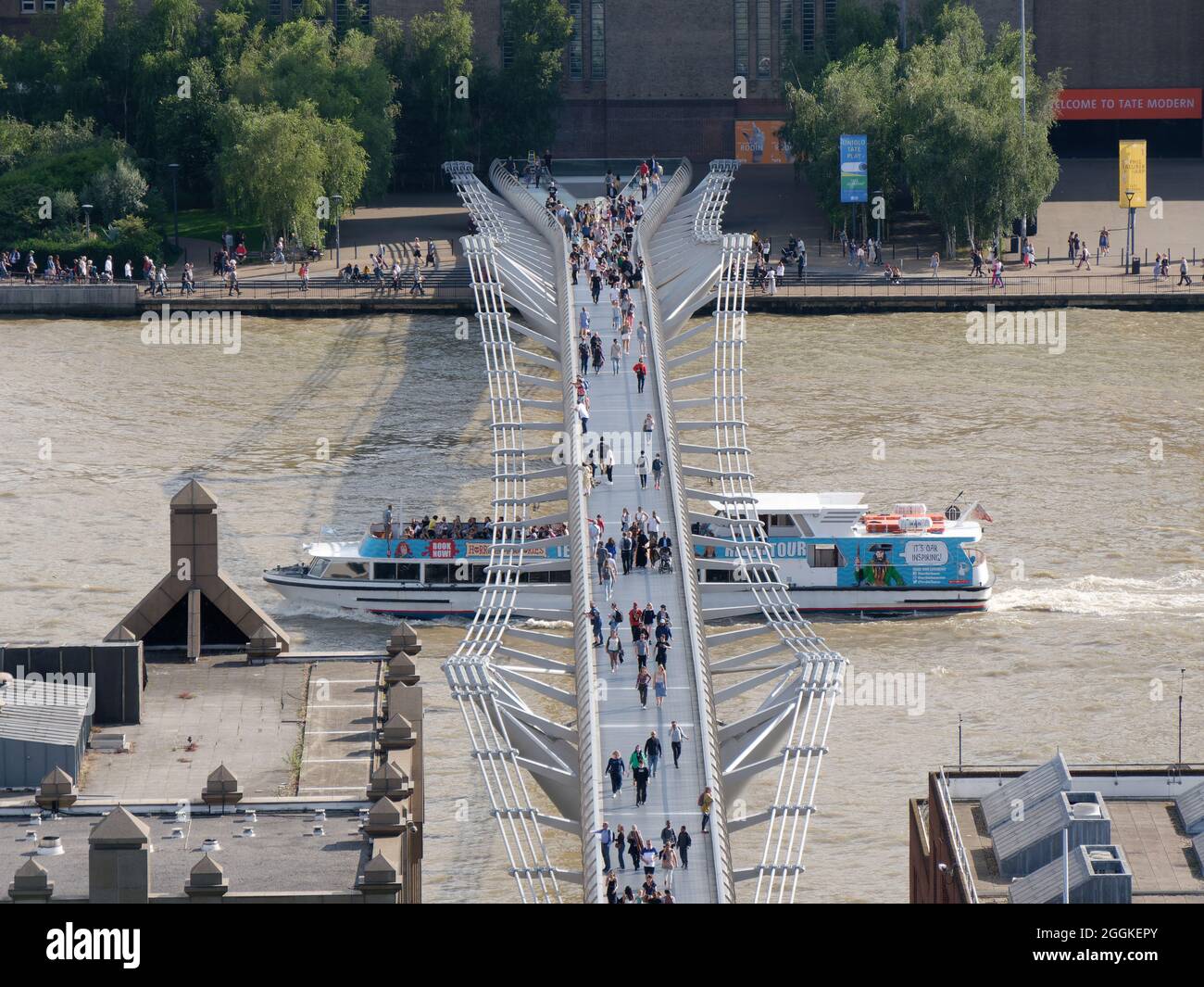 London, Greater London, England, August 24 2021: Aerial view of the Millennium Bridge on the River Thames as a boat passes under the bridge. Stock Photo